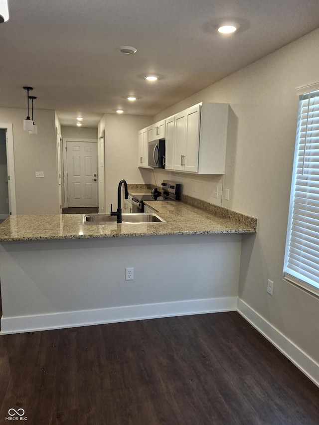 1974 Ralston Ave, Indianapolis, IN 46218 - kitchen featuring appliances with stainless steel finishes, light stone countertops, a peninsula, dark wood-style flooring, and recessed lighting