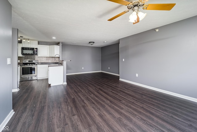 kitchen featuring baseboards, stainless steel electric range, open floor plan, black microwave, and tasteful backsplash