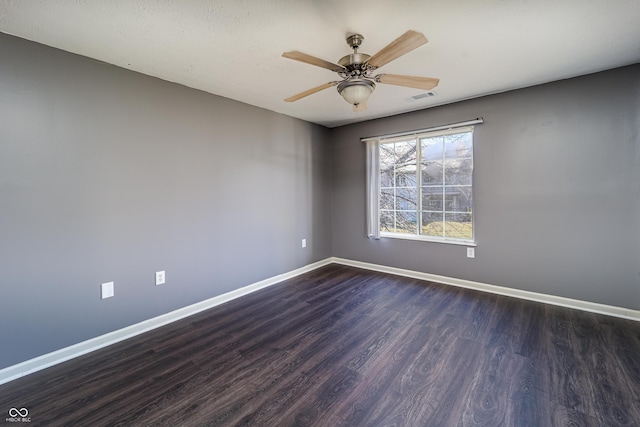 spare room with visible vents, baseboards, ceiling fan, and dark wood-style flooring