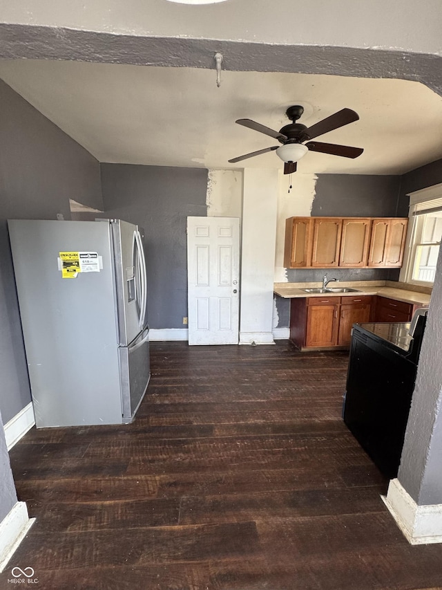 kitchen with stainless steel fridge, light countertops, dark wood-type flooring, and a sink