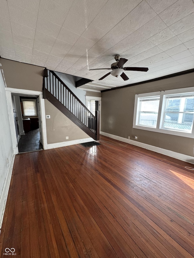 unfurnished living room featuring stairway, baseboards, ceiling fan, and hardwood / wood-style flooring