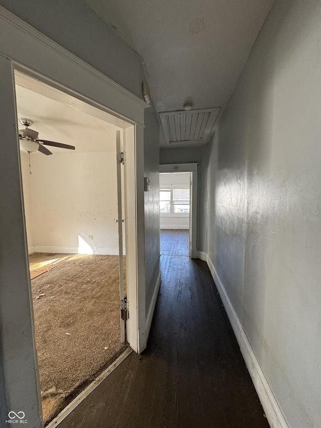 corridor with attic access, baseboards, and wood-type flooring