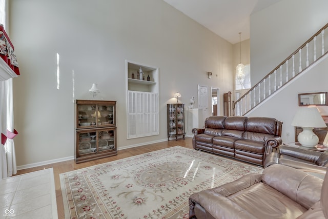 living area with stairway, a high ceiling, built in features, and baseboards