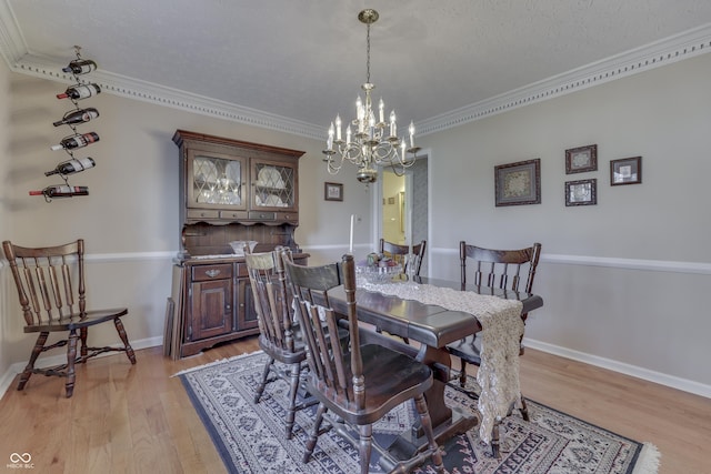 dining room with crown molding, baseboards, light wood-style floors, a notable chandelier, and a textured ceiling