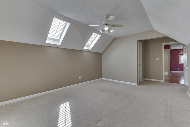 bonus room featuring a textured ceiling, baseboards, light colored carpet, ceiling fan, and vaulted ceiling