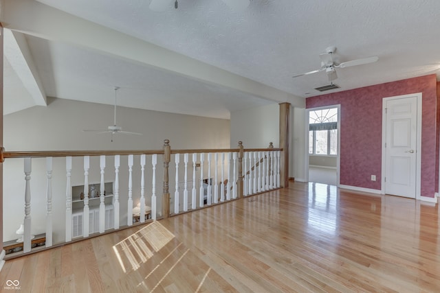 spare room featuring wood finished floors, visible vents, baseboards, ceiling fan, and a textured ceiling