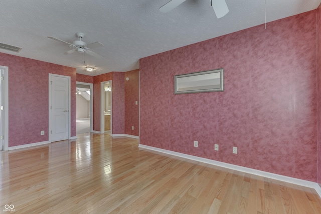 spare room featuring visible vents, light wood-style flooring, a textured ceiling, and ceiling fan