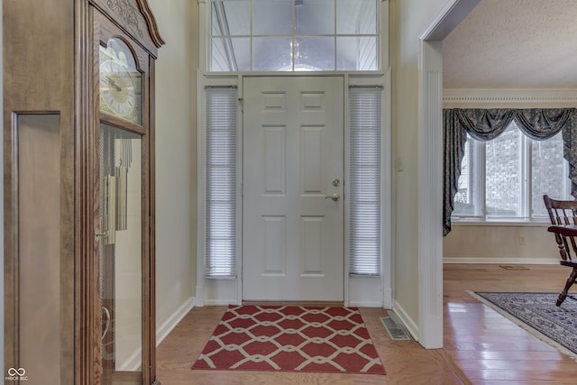 entryway with visible vents, wood finished floors, baseboards, and a textured ceiling