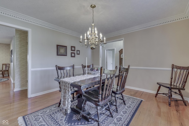 dining room featuring light wood-style flooring, baseboards, a chandelier, and ornamental molding