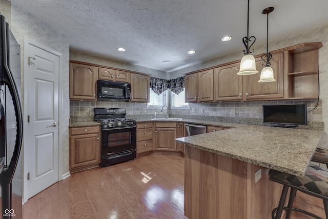 kitchen with light wood-type flooring, black appliances, a sink, open shelves, and a peninsula