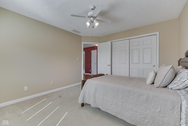 bedroom featuring visible vents, light carpet, a ceiling fan, a closet, and baseboards