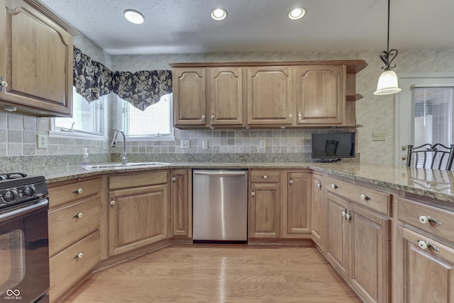 kitchen featuring light stone counters, light wood finished floors, a sink, black range with gas cooktop, and stainless steel dishwasher