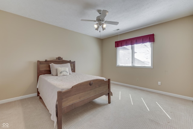 bedroom featuring visible vents, baseboards, ceiling fan, a textured ceiling, and light carpet