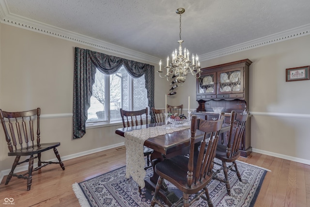 dining area featuring a notable chandelier, light wood-type flooring, and a textured ceiling