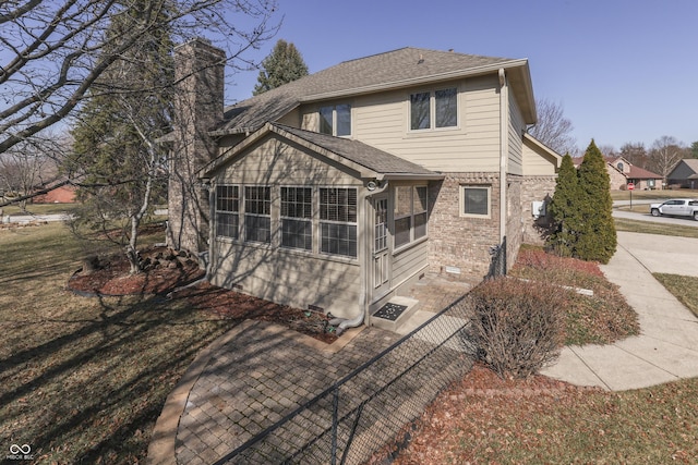 back of house with brick siding, a chimney, and roof with shingles