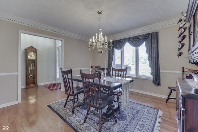 dining room with ornamental molding, a textured ceiling, an inviting chandelier, light wood finished floors, and baseboards