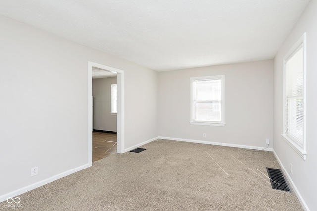 spare room featuring visible vents, carpet flooring, and baseboards