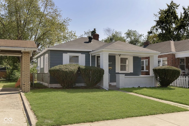 bungalow featuring brick siding, a chimney, a front lawn, and fence