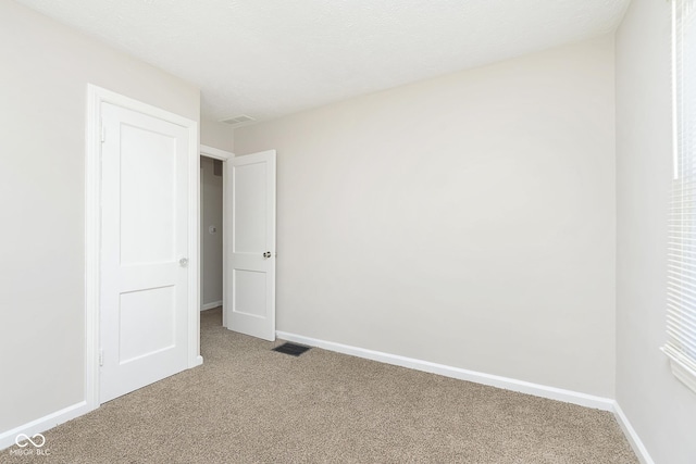 unfurnished room featuring visible vents, baseboards, and light colored carpet