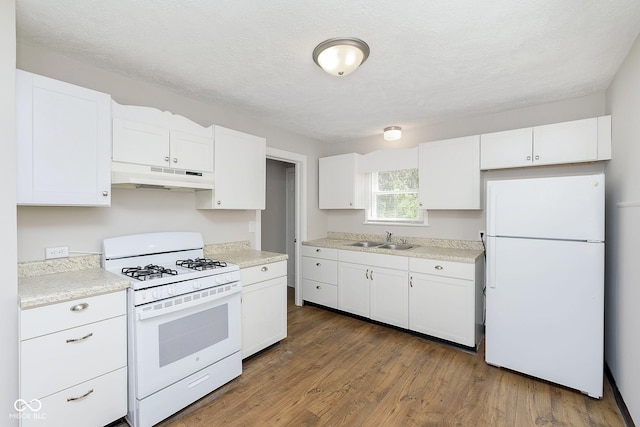 kitchen featuring white appliances, white cabinets, under cabinet range hood, and a sink