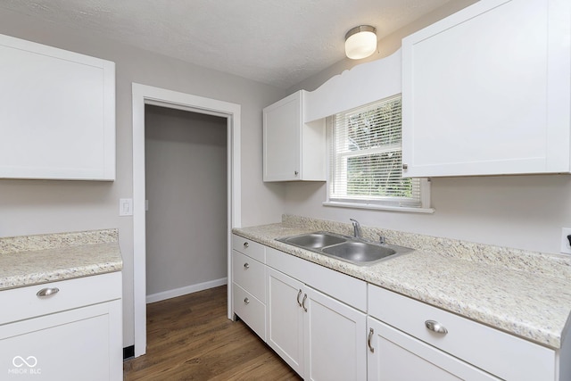 kitchen featuring a sink, a textured ceiling, white cabinetry, light countertops, and dark wood-style flooring