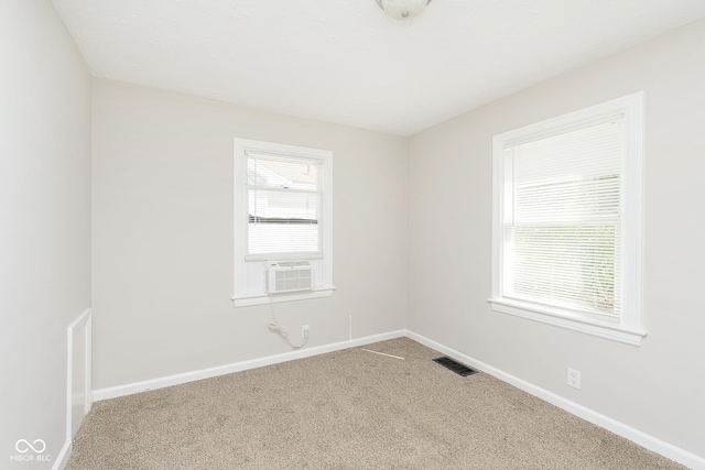 spare room featuring carpet flooring, plenty of natural light, baseboards, and visible vents