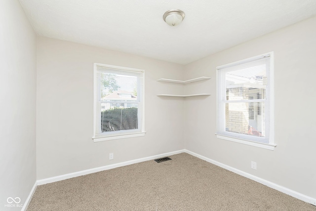 carpeted spare room featuring visible vents and baseboards