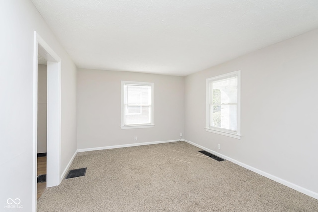 carpeted spare room featuring visible vents and baseboards