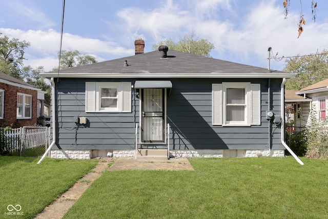 back of house featuring a lawn, a shingled roof, a chimney, and fence