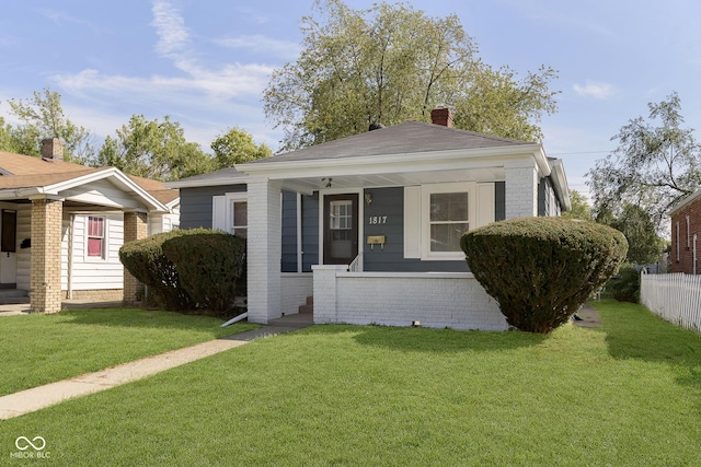 bungalow with brick siding, a front yard, and fence