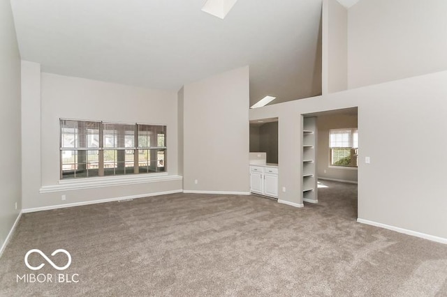 unfurnished living room featuring baseboards, built in features, a skylight, and carpet