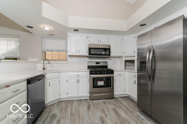 kitchen with light wood-style floors, appliances with stainless steel finishes, light countertops, and white cabinetry