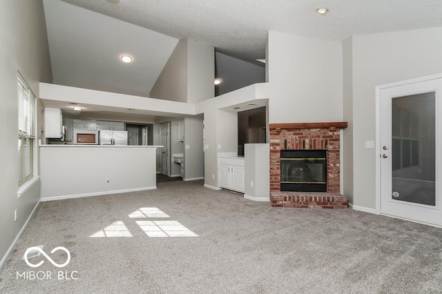 unfurnished living room with baseboards, carpet floors, high vaulted ceiling, and a brick fireplace