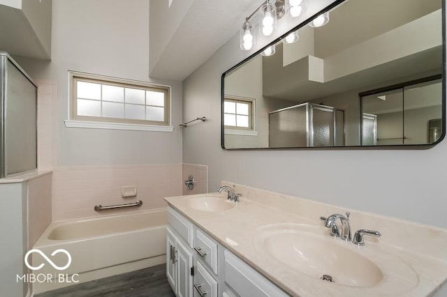 bathroom featuring a bath, a stall shower, double vanity, and a sink