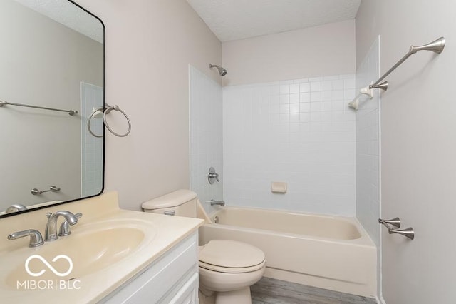 bathroom with toilet, a textured ceiling, wood finished floors, tub / shower combination, and vanity