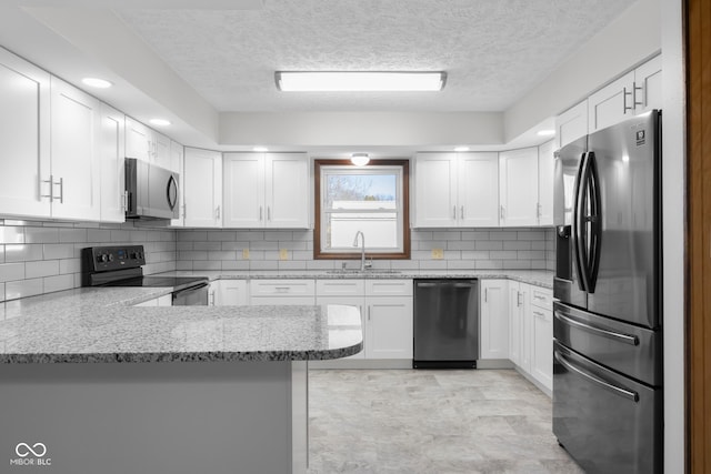 kitchen with a sink, appliances with stainless steel finishes, a peninsula, and white cabinetry