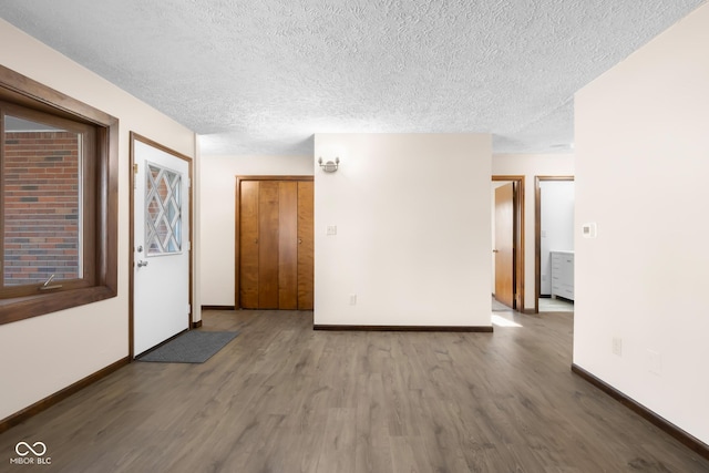 spare room featuring a textured ceiling, baseboards, and wood finished floors