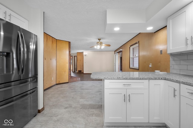 kitchen featuring a peninsula, white cabinets, a ceiling fan, and stainless steel fridge