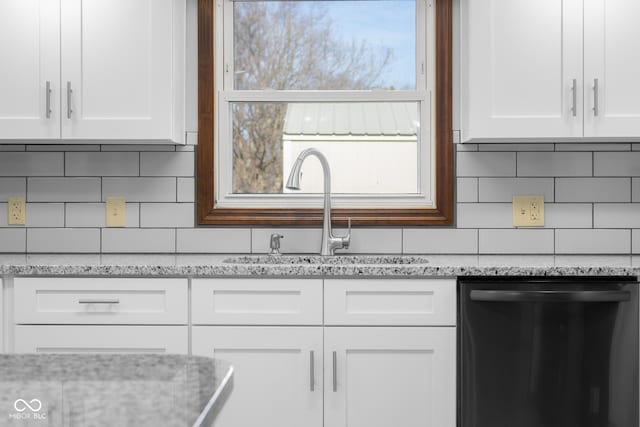 kitchen with dishwashing machine, white cabinets, backsplash, and a sink