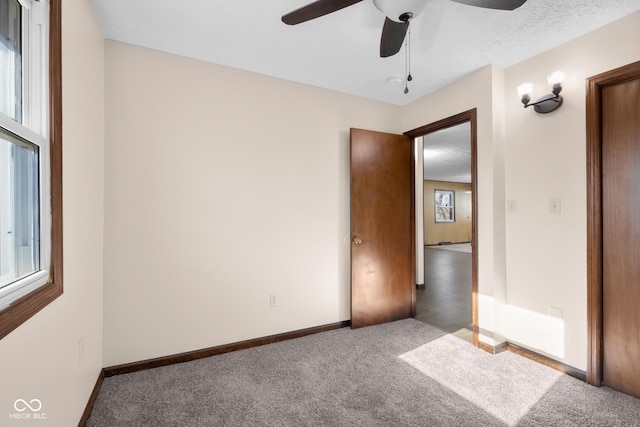 unfurnished bedroom with multiple windows, baseboards, carpet floors, and ceiling fan