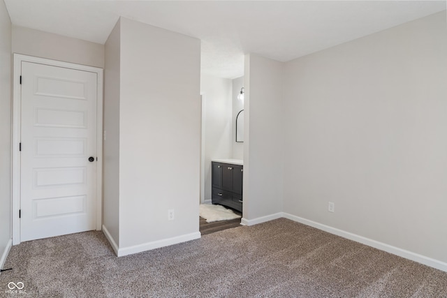 unfurnished bedroom featuring connected bathroom, baseboards, and carpet