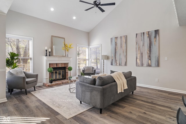 living area with high vaulted ceiling, a healthy amount of sunlight, dark wood-style floors, and a fireplace