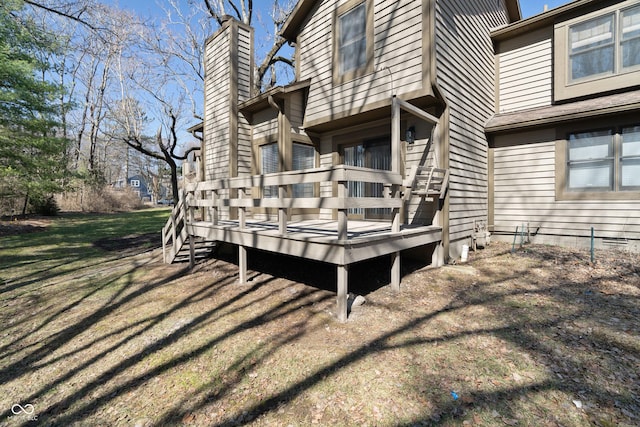 view of side of property featuring a wooden deck, a lawn, and a chimney