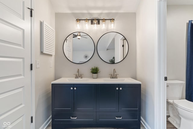 full bathroom with double vanity, toilet, baseboards, and a sink