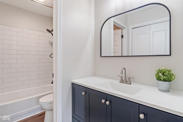 bathroom featuring wood finished floors, toilet, vanity, and washtub / shower combination