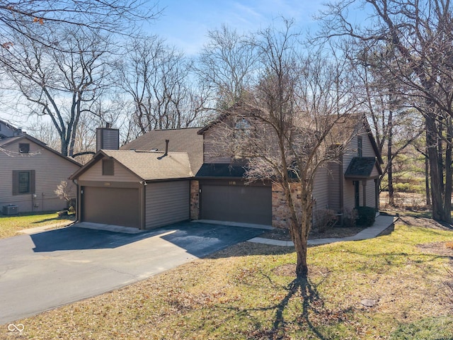 view of front of house with a front lawn, a garage, roof with shingles, and a chimney