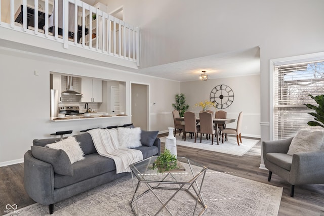 living area featuring a high ceiling, baseboards, and wood finished floors