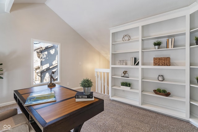 carpeted office with vaulted ceiling, built in shelves, and baseboards