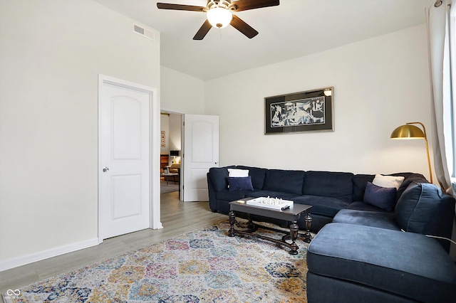 living area with visible vents, baseboards, vaulted ceiling, wood finished floors, and a ceiling fan