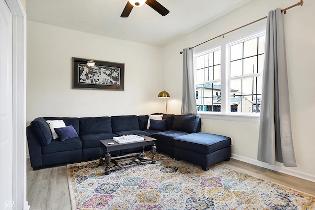 living room featuring baseboards, a ceiling fan, and wood finished floors